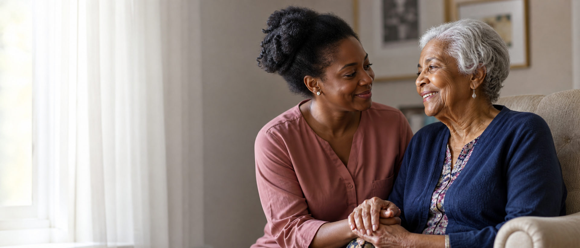 A Heart to Home caregiver holding hands with a smiling senior client at home in Los Angeles.